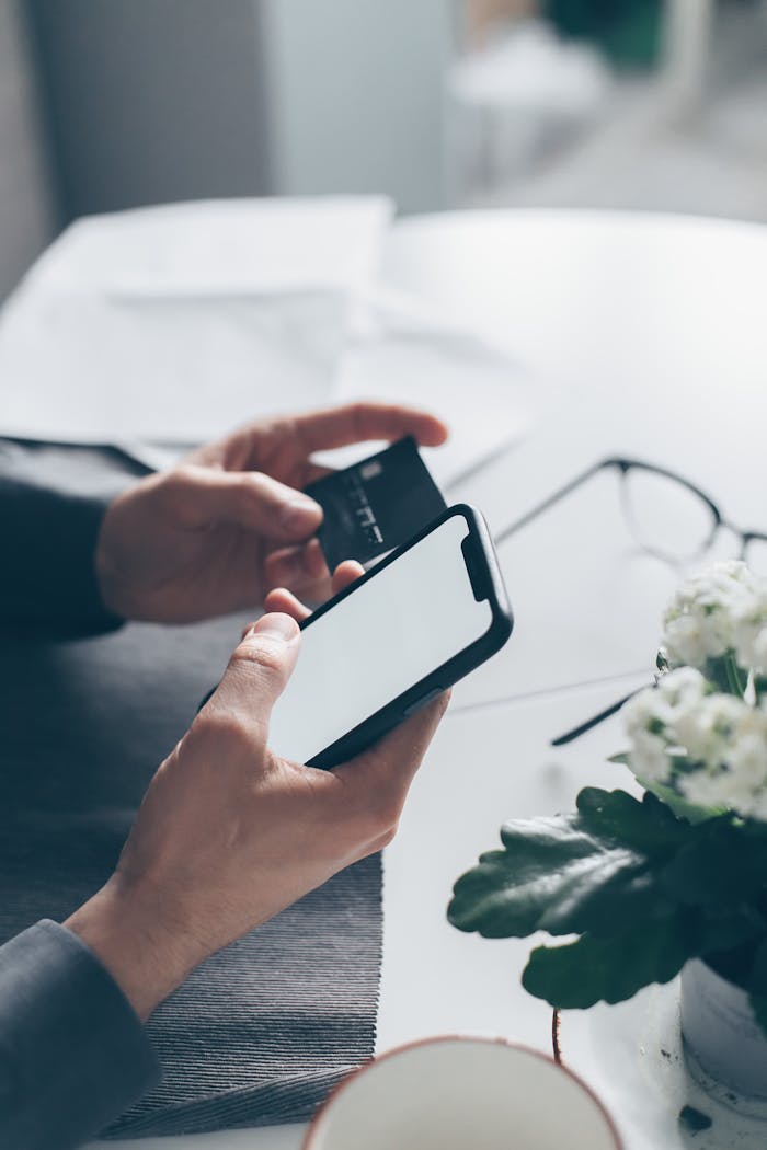 Close-up of hands holding a smartphone and a credit card, implying online payment.